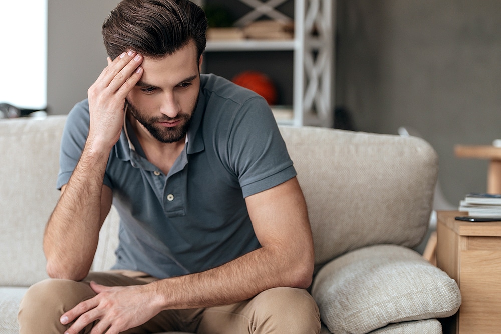 homem jovem sentado pensativo | Você sabe qual a relação entre as verrugas genitais e o HPV?
