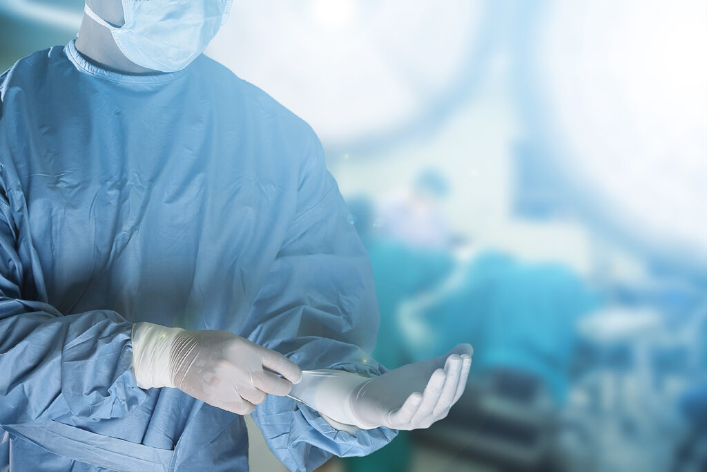 Médico colocando luva no centro cirúrgico